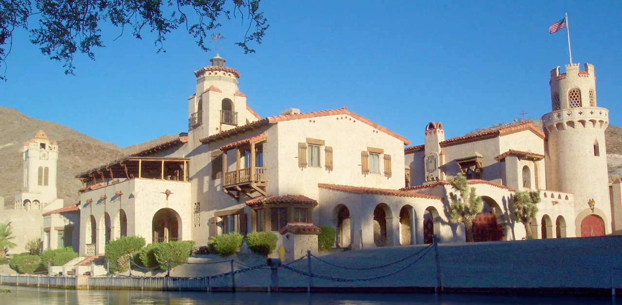 Scotty's Castle, a 1920s Spanish-revival mansion in Death Valley National Park, with palm-tree gardens and desert mountains beyond